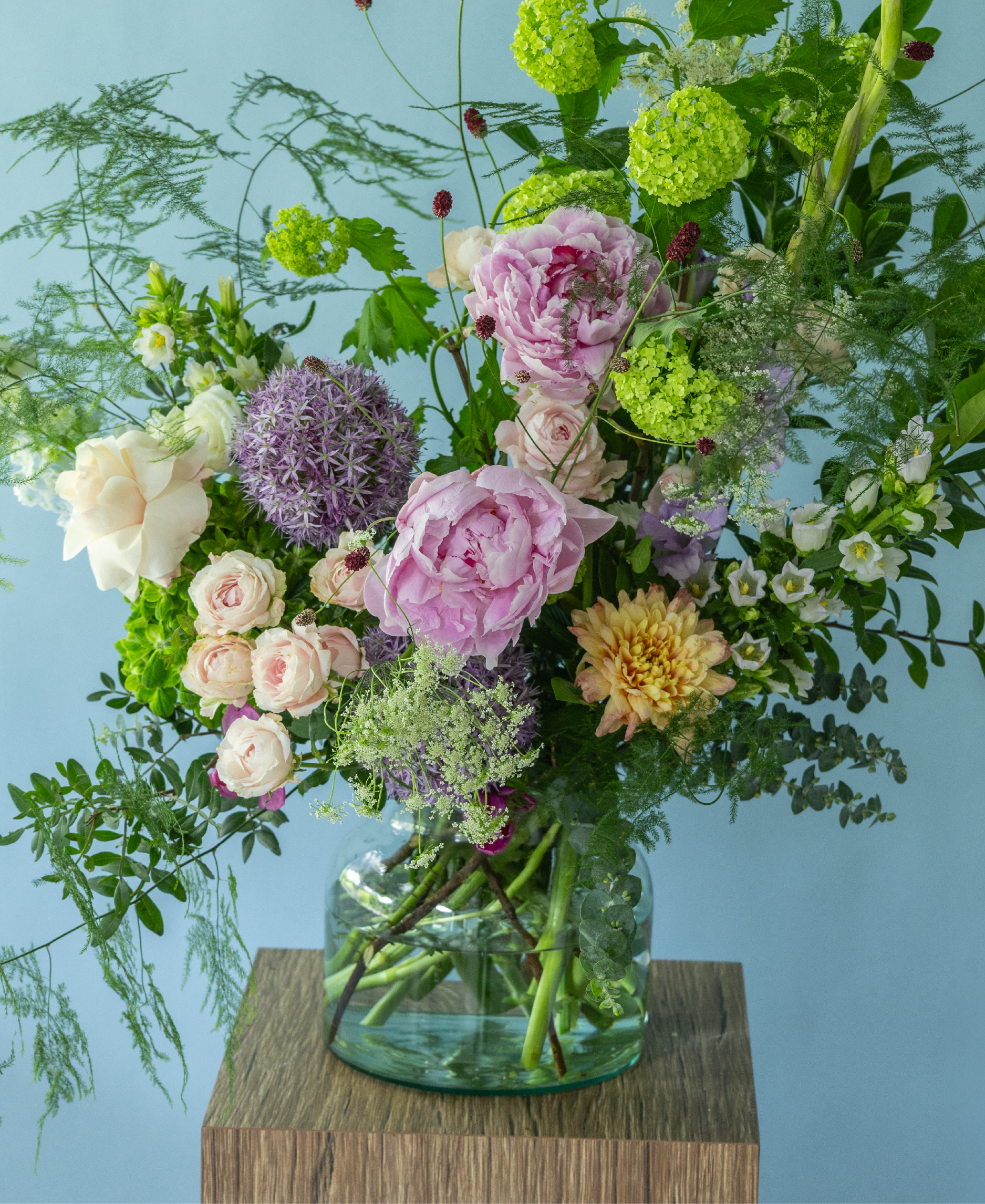 Garden-style summer flowerarrangement by Charlotte Puxley Flowers featuring premium seasonal peonies, dancing textures, fresh green foliage, and soft pastel flowers.