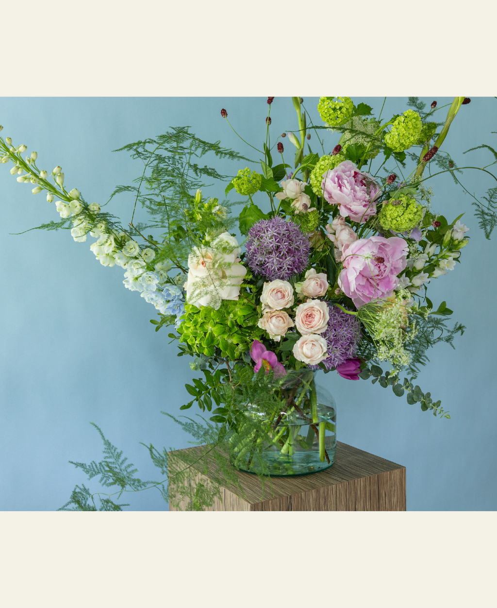 Garden-style summer arrangement by Charlotte Puxley Flowers featuring premium seasonal peonies, dancing textures, fresh green foliage, and soft pastel flowers.
