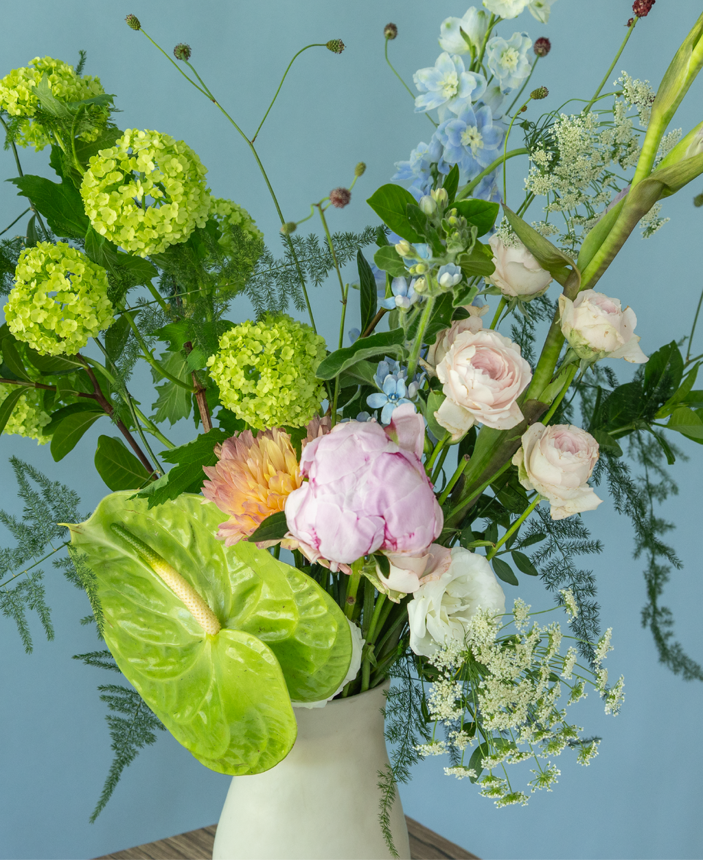 Elegant peony flower arrangement in a hand-crafted ceramic vase by Charlotte Puxley Flowers Singapore, showcasing seasonal pink peonies, spray roses, and lush summer greenery.